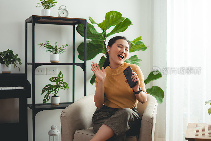 Asian woman happy with relax time using earbuds listening to music at home.